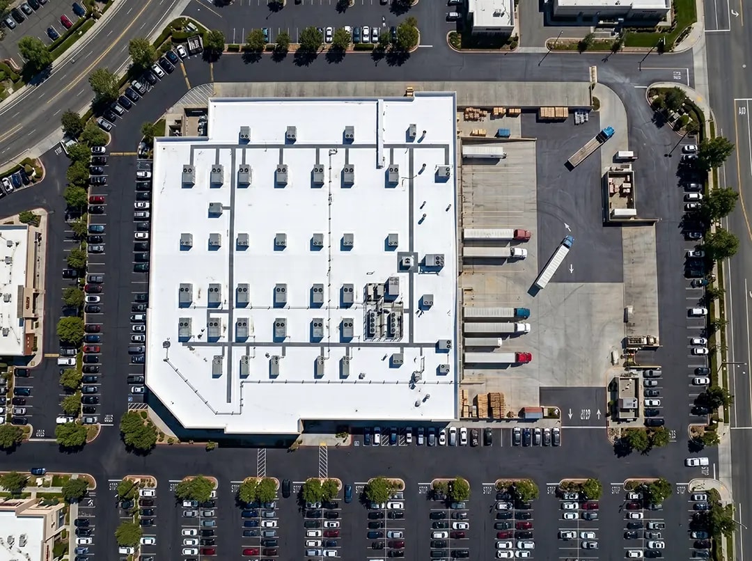 Aerial view of a commercial building with a white roof featuring HVAC units, showcasing advanced roofing technology related to NanoTech Materials' innovative coating solutions.