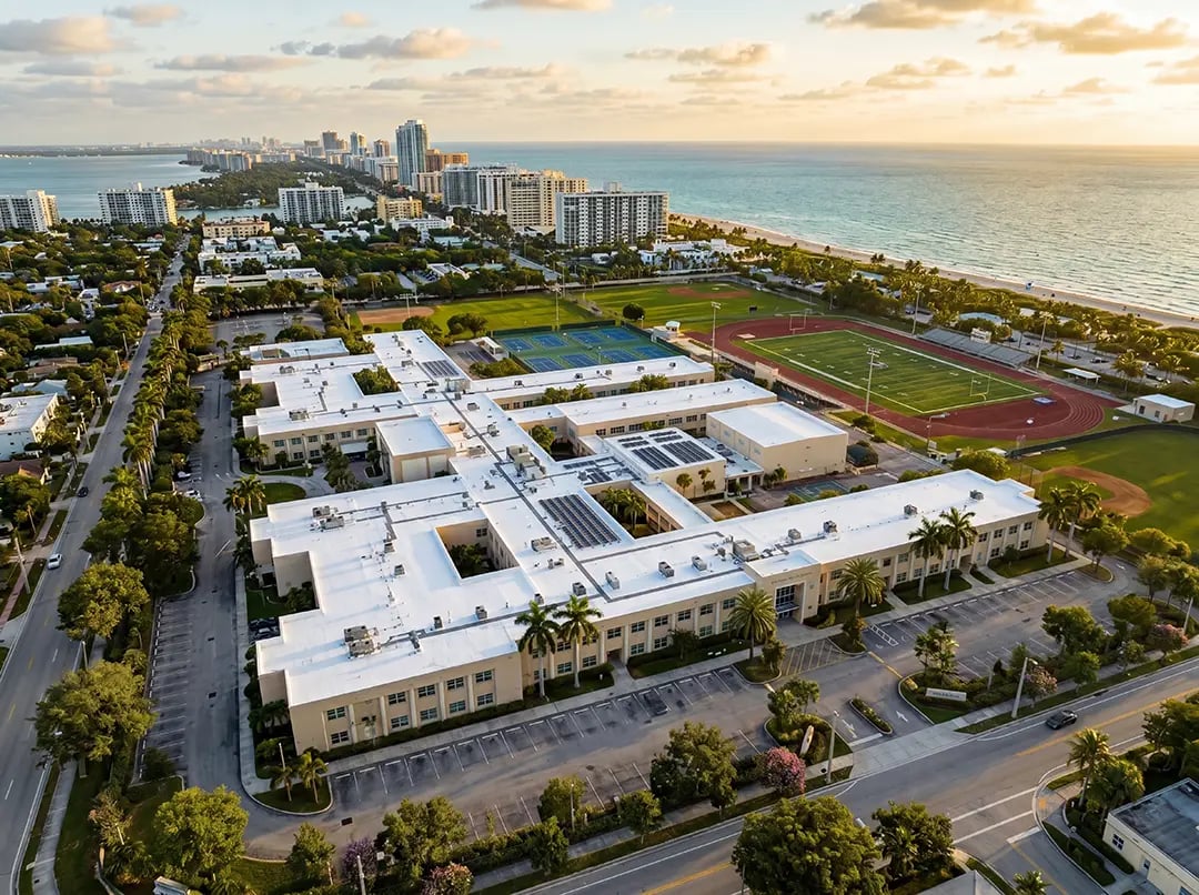 Aerial view of a white cool roofing system on a commercial building, surrounded by palm trees, showcasing NanoTech Materials' innovative thermal insulation solutions for energy efficiency.
