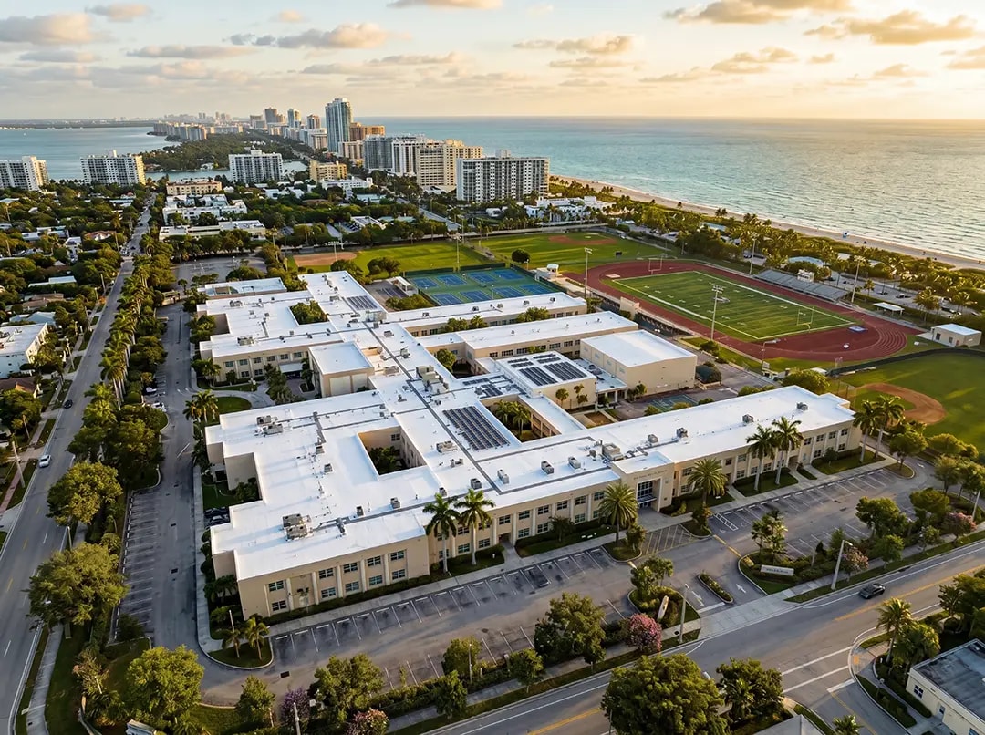 Aerial view of a white cool roofing system on a commercial building, surrounded by palm trees, showcasing NanoTech Materials' innovative thermal insulation solutions for energy efficiency.
